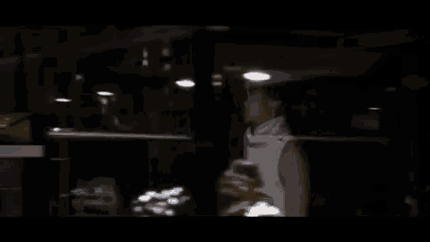 a woman is sitting at a table in a dark room with her head down .