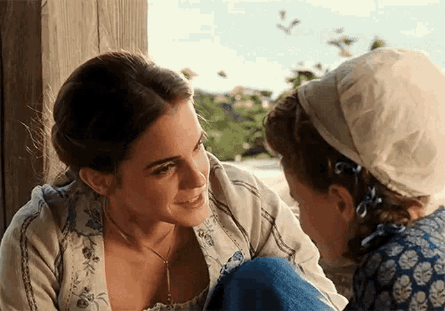 two women are sitting next to each other and talking to each other .