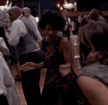 a woman in a floral dress is dancing in a crowd of people