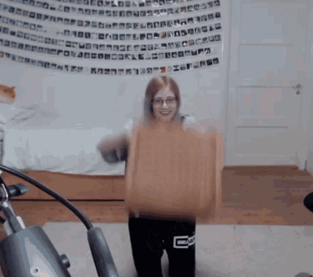 a girl with glasses is holding a piece of cardboard in front of a wall with letters on it