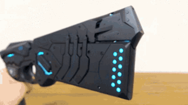 a person is holding a black and blue futuristic gun
