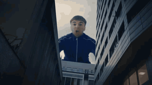 a man in a blue jacket stands between two buildings
