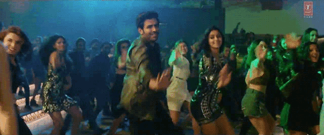 a group of people are dancing in a club with a t on the bottom right