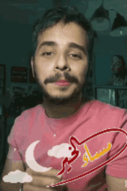 a man with a beard and mustache wearing a pink shirt with a crescent moon on it
