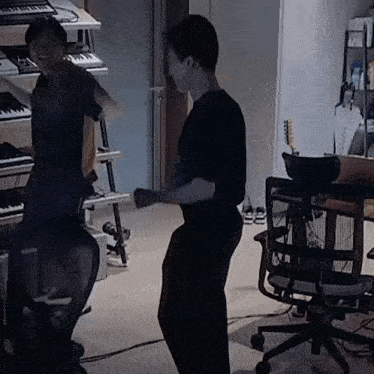 a man in a black shirt is standing next to another man in a black shirt in a dark room .