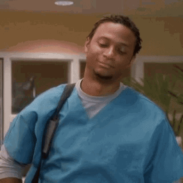 a man in a blue scrub top is standing in a room .