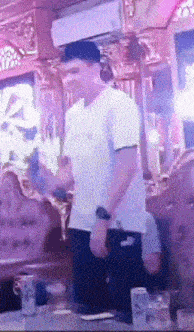 a man in a white t-shirt is dancing in a room with purple lights