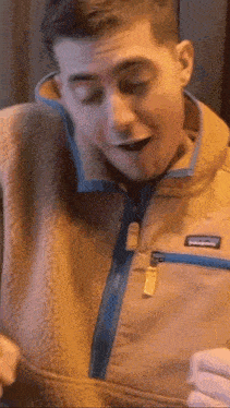 a man wearing a patagonia jacket is holding a piece of paper in his hand .