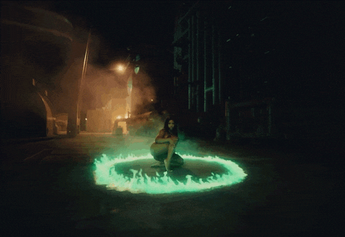 a naked woman is kneeling in a circle of green flames