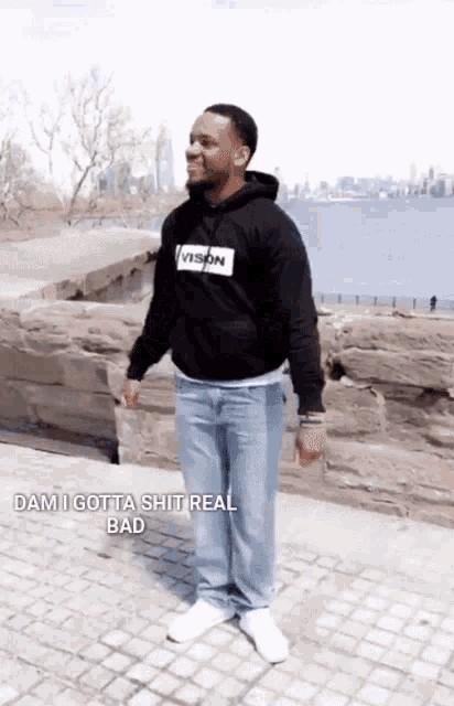 a man wearing a vision hoodie is standing on a sidewalk