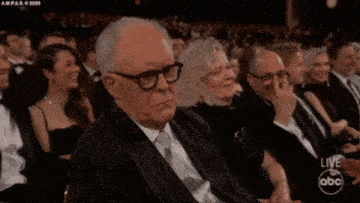 an older man in a suit and tie is sitting in a crowd watching a live abc show