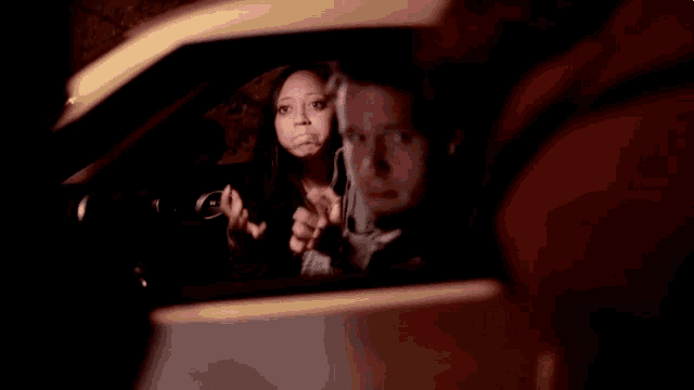 a woman is sitting in a car with her hands up