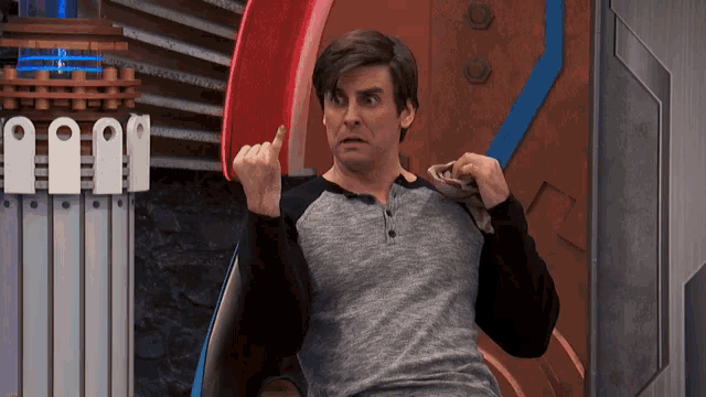 a man in a gray shirt is sitting in a chair and making a face