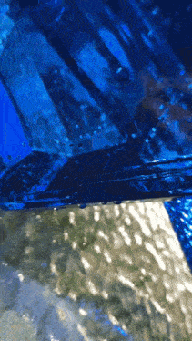 a close up of a blue water surface with bubbles coming out of it