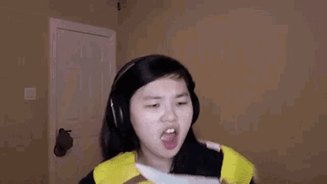 a young woman wearing headphones is holding a knife in her hand .