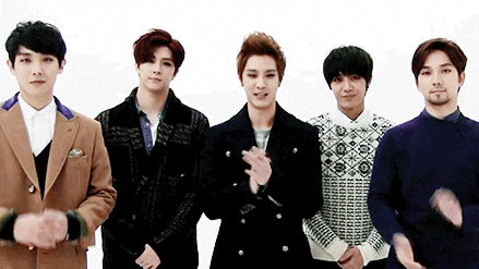 a group of young men are standing next to each other and clapping their hands