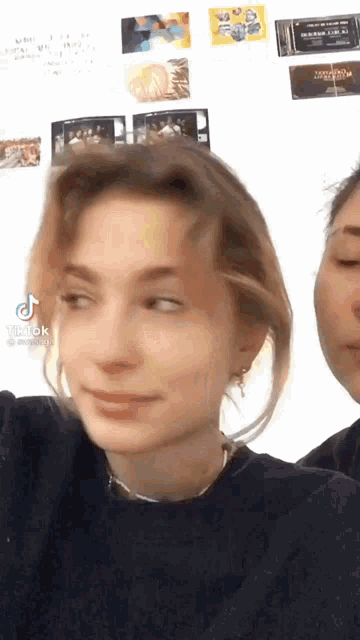 a woman is standing next to another woman and looking at the camera .