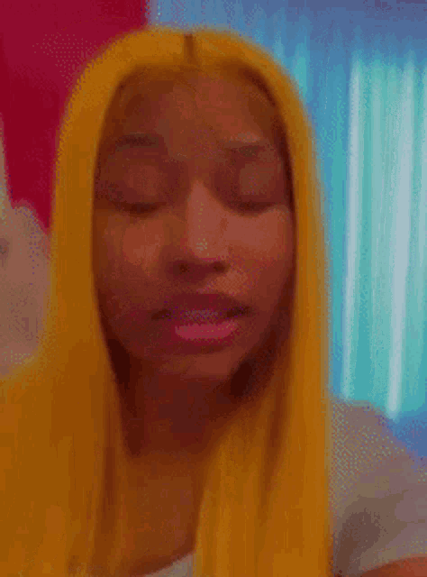 a close up of a woman 's face with her eyes closed and yellow hair .