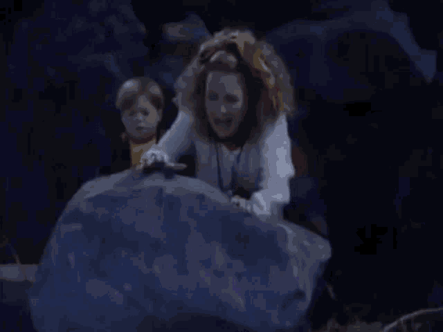 a woman in a colorful costume is pushing a giant ice ball