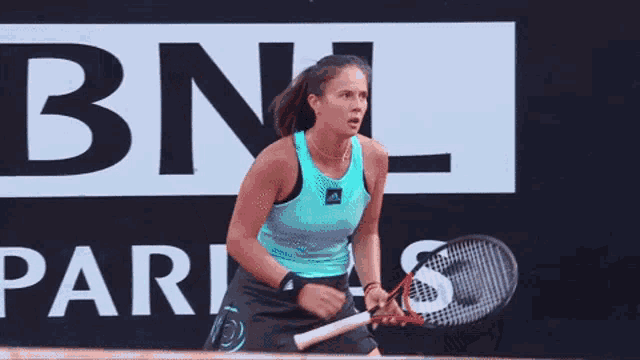 a woman in a blue tank top is holding her fist in the air