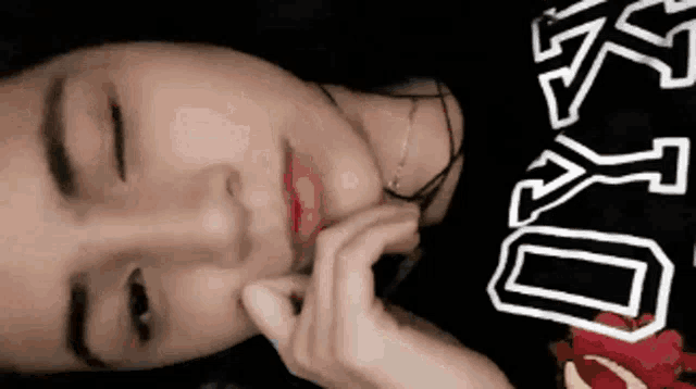 a close up of a woman 's face with her eyes closed and her hand on her face .