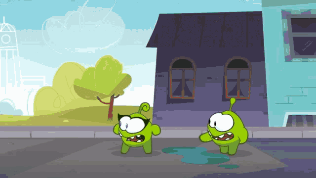 a couple of green cartoon characters standing on a street