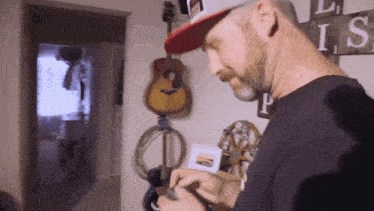 a man in a hat is looking at a picture in front of a guitar