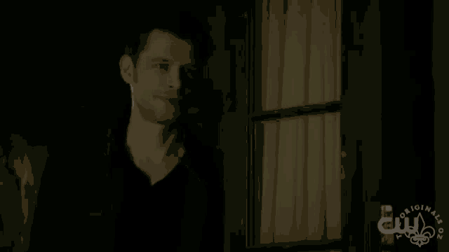 a man in a black jacket is standing in front of a window with the word originals on it