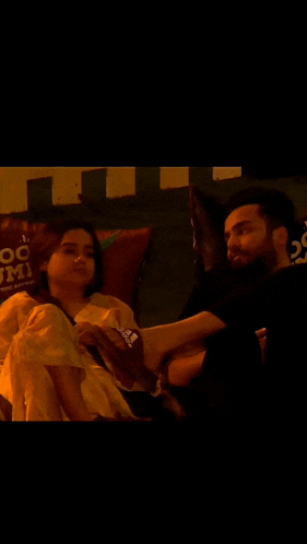 a man and a woman are sitting on a couch in a dark room .