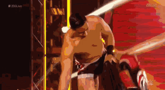 a shirtless wrestler in a ring with # 205live written on the bottom