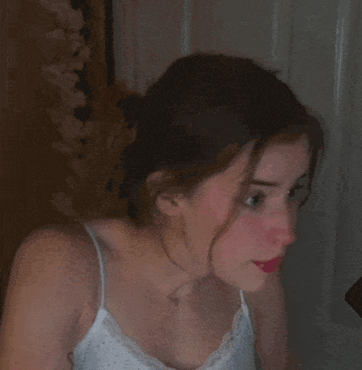 a woman in a white tank top is making a funny face while looking at the camera .