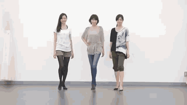 three women are standing next to each other in a room and dancing .