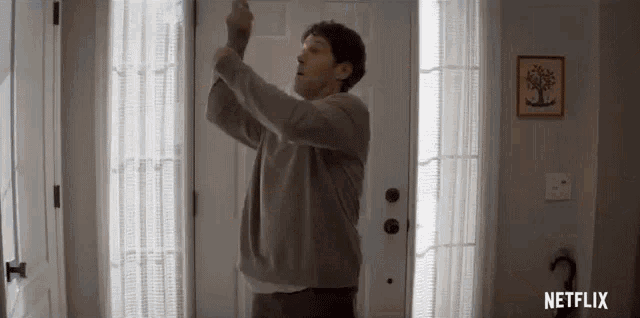 a man is standing in front of a door in a room holding a remote control .