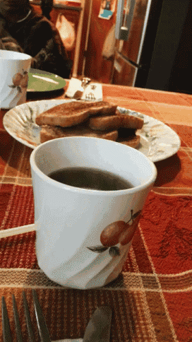 a cup of coffee sits next to a plate of toast