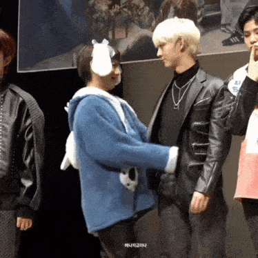 a group of young men are standing next to each other and one of them is wearing bunny ears and a blue jacket