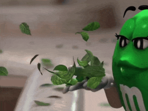 a green m & m holding some green leaves