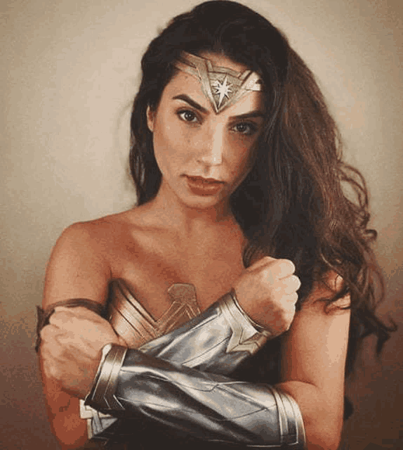 a woman in a wonder woman costume is posing for a picture with her hands on her chest .