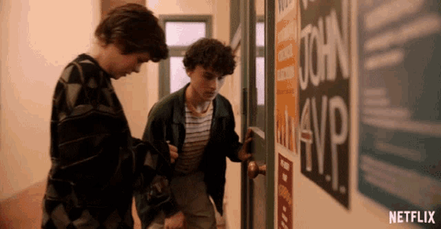 two boys are standing in a hallway with a netflix logo on the bottom right