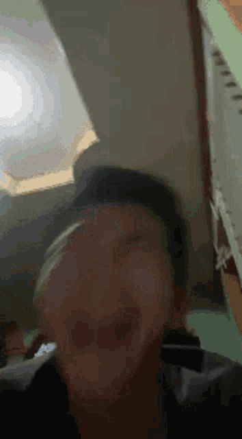 a man is making a funny face in a room with a light behind him .