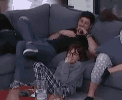a group of people are sitting on a couch with their feet up .