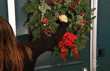 a woman hangs a wreath on a door that says t.s.