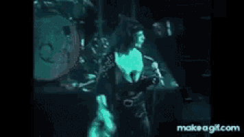 a man is singing into a microphone on a stage in front of a drum .