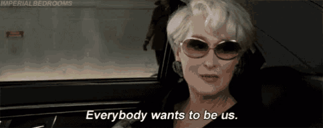 a woman wearing sunglasses is sitting in a car and says everybody wants to be us