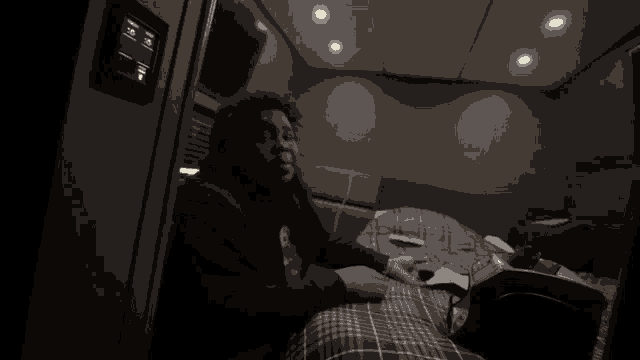 a black and white photo of a man sitting on a bed holding a gun
