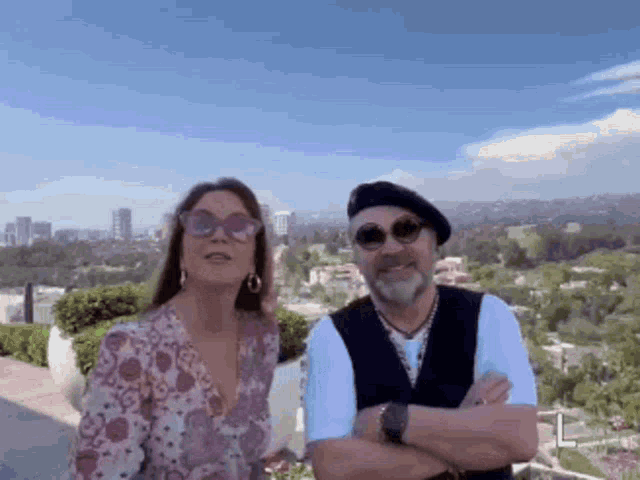 a man and a woman are posing for a picture in front of a city skyline