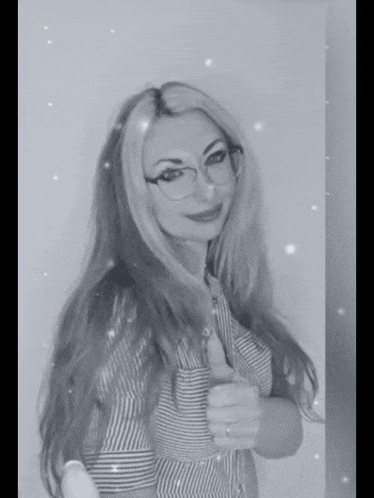 a woman in glasses is giving a thumbs up in a black and white photo .