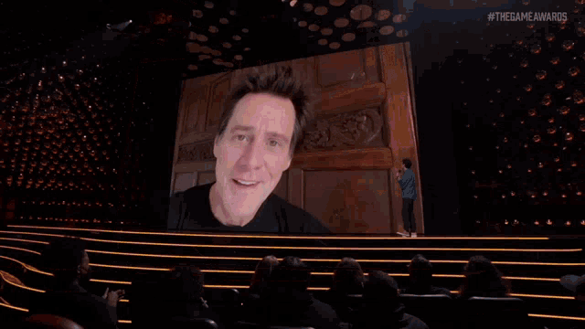 a man stands on a stage with a microphone in front of a large screen that says #thegameawards on it
