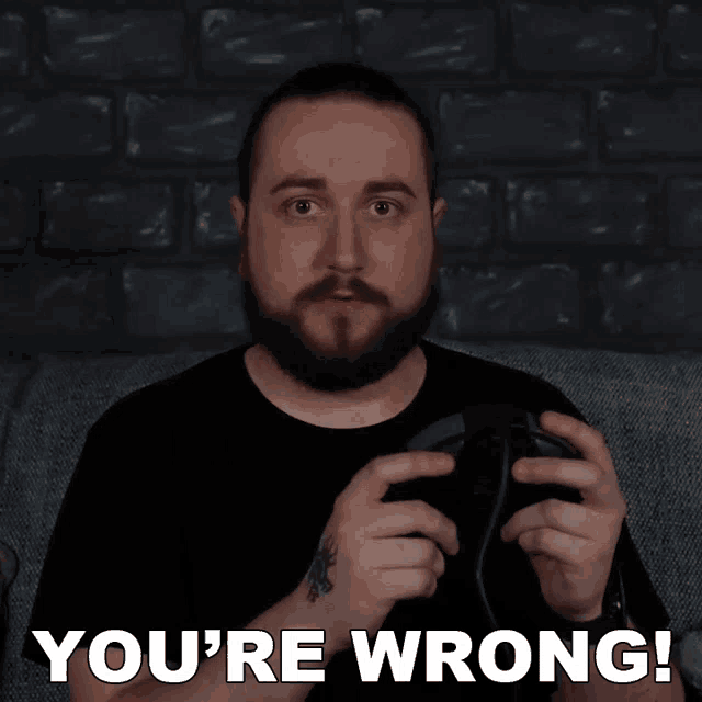 a man with a beard is holding a game controller and says you 're wrong