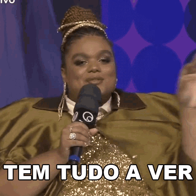 a woman holding a microphone with the words tem tudo a ver written below her