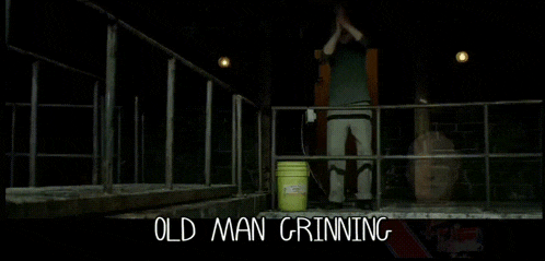 a man is standing in a dark room with the words old man grinning